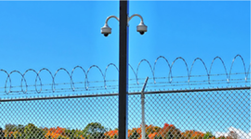 security cameras above a barb wire fence
