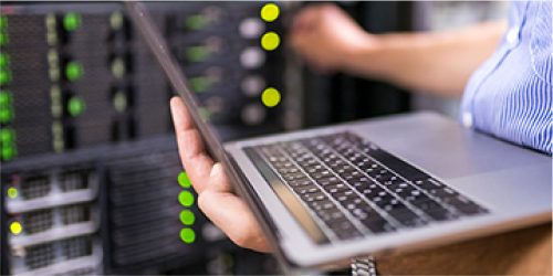 an IT employee standing holding a laptop